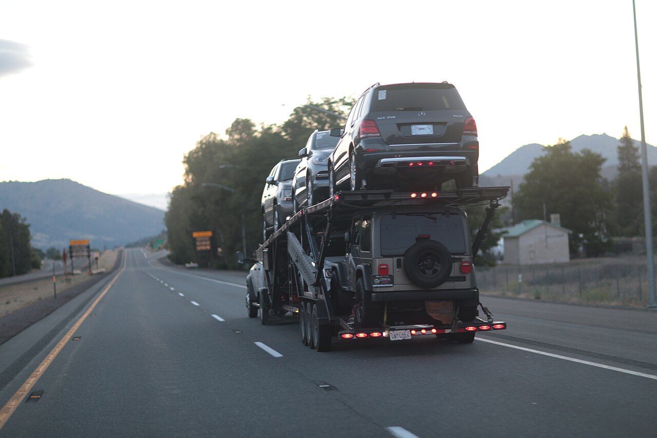 A loaded open car carrier traveling along a California highway