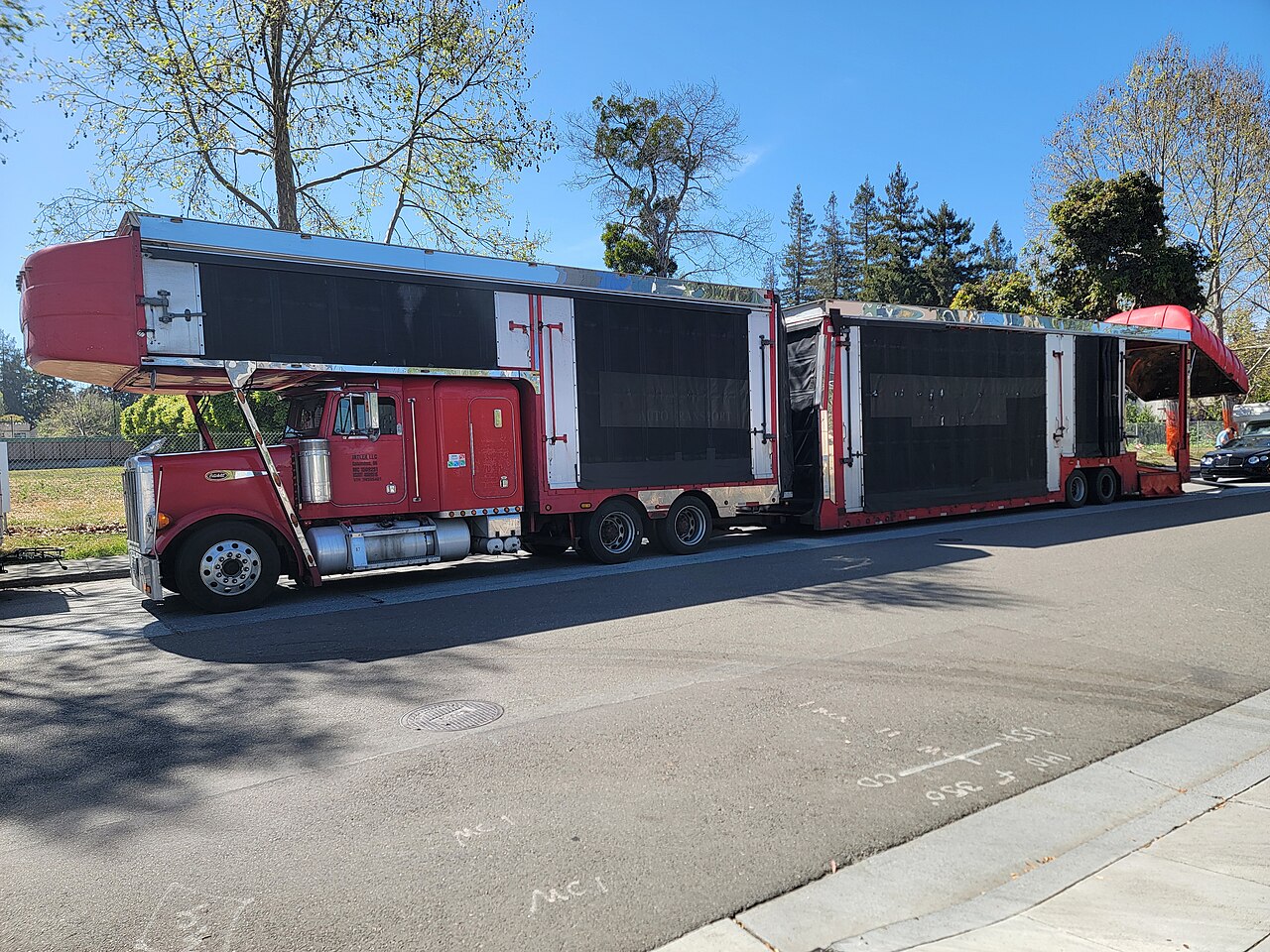 A red Peterbilt car hauler with enclosed upper and lower vehicle decks